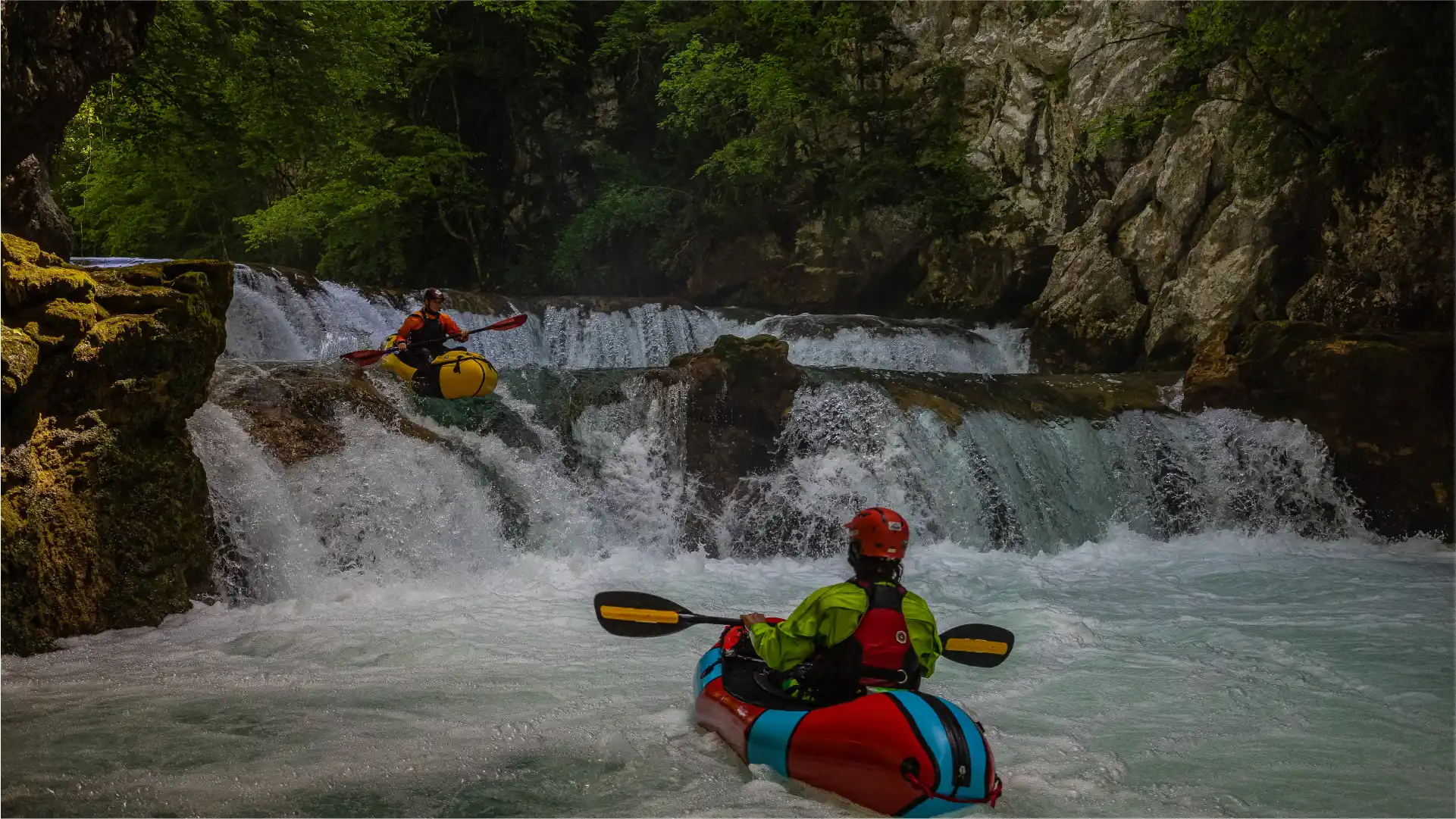 A person in a packraft, watching another person in a packraft who is going down a waterfall on Mreznica river