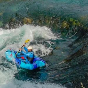 A person in a blue packraft, going down a rapid on Zrmanja river