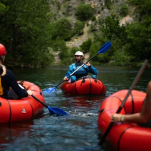 A guide, in a packraft, speaking to guests on the river who are also in packrafts.