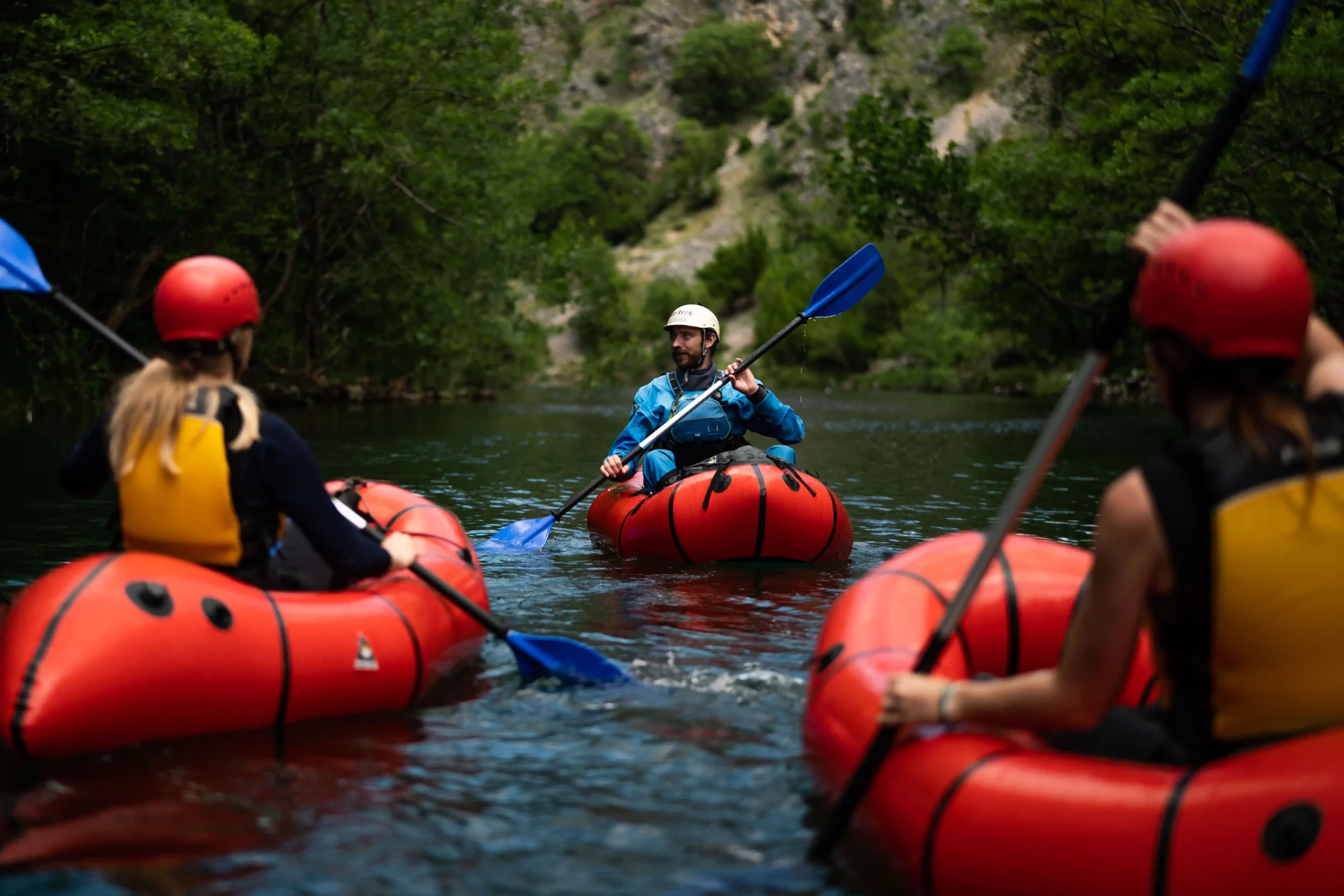 A guide, in a packraft, speaking to guests on the river who are also in packrafts.