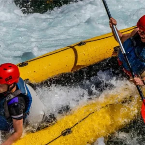 Two people smiling and laughing in a kayak while going down a rapid on Zrmanja river