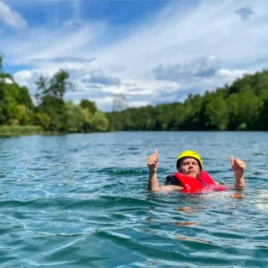 Čovjek u rijeci Mrežnici sa sigurnosnim prslukom i sa palčevima ruke gore