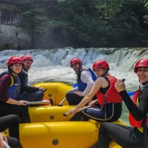 Grupa ljudi u raftu sa slapom u pozadini