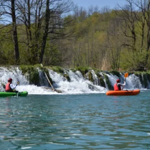 Two people in packraft boats paddling next to the waterfall
