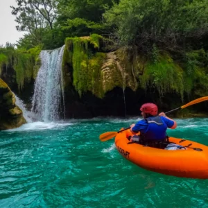 Person paddling towards a waterfall in a packraft boat