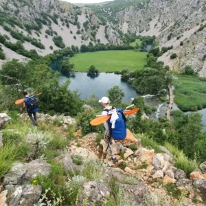Two people hiking through the canyon while carrying boats and equipment