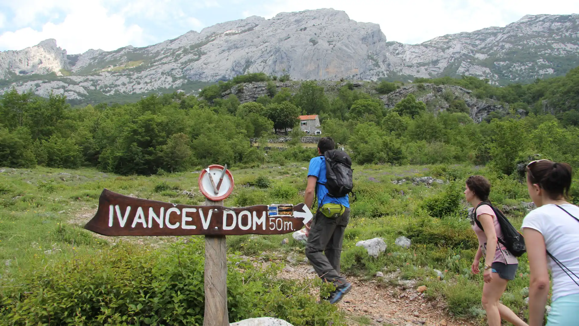 Group of people hiking on Paklenica and a big sing for a mountain hut in the foreground