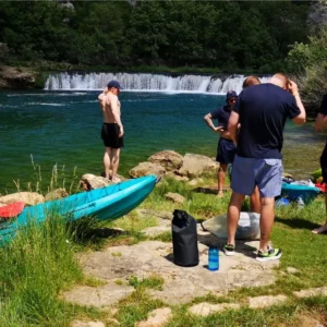Group of people relaxing by the side of the river with the waterfall in the background
