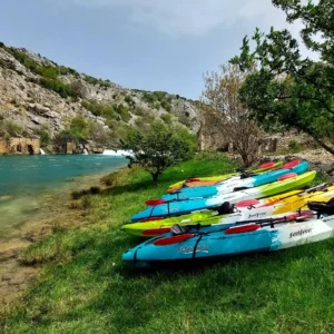 Sea kayaks on the side of the river with the waterfall in the background