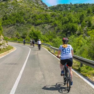 Grupa ljudi biciklira niz cestu