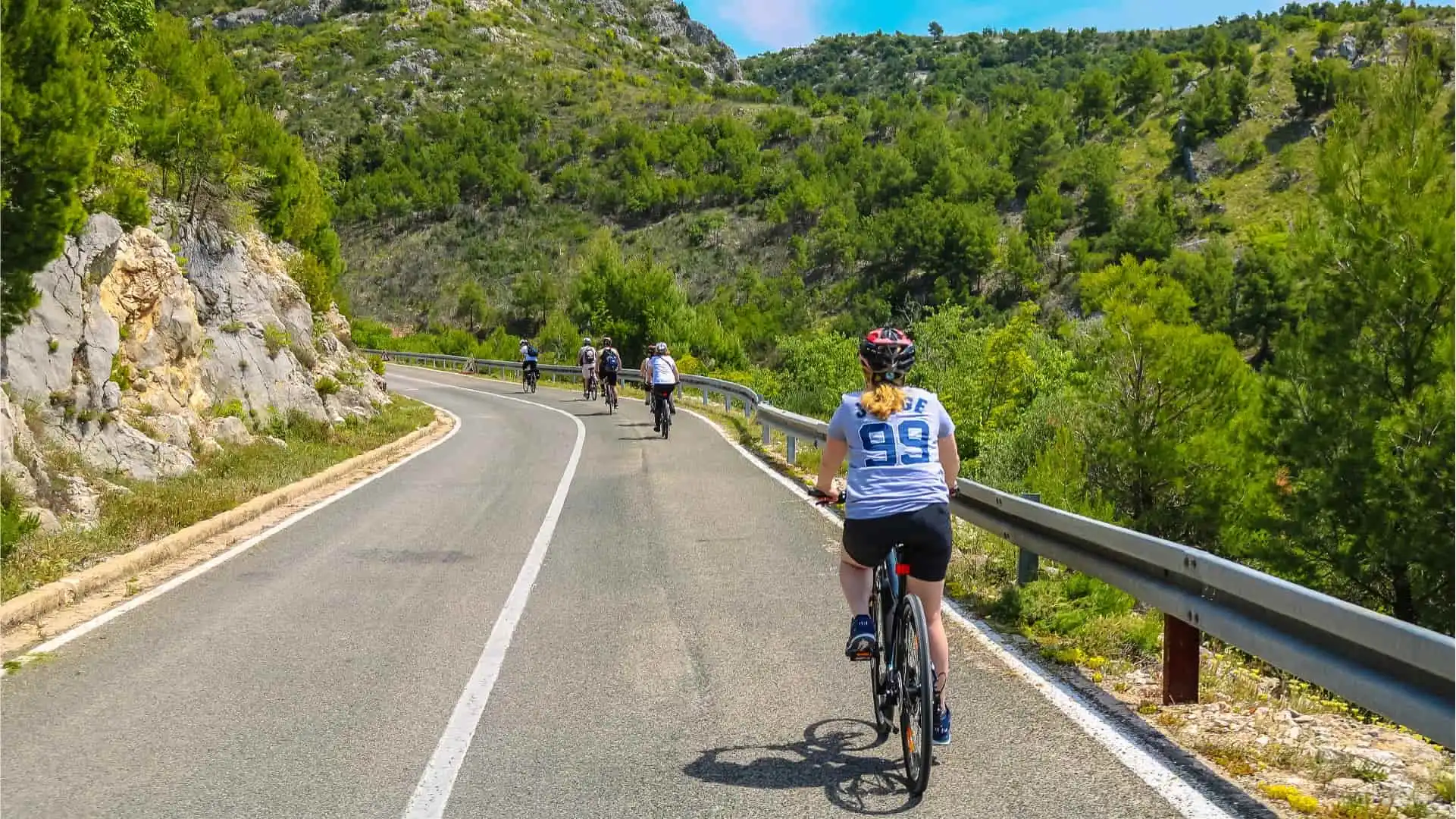 Grupa ljudi biciklira niz cestu