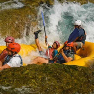 Grupa ljudi u raftu ide niz brzac na rijeci Uni